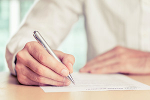 Businessman signing a document. Tinted photo, shallow depth of field.