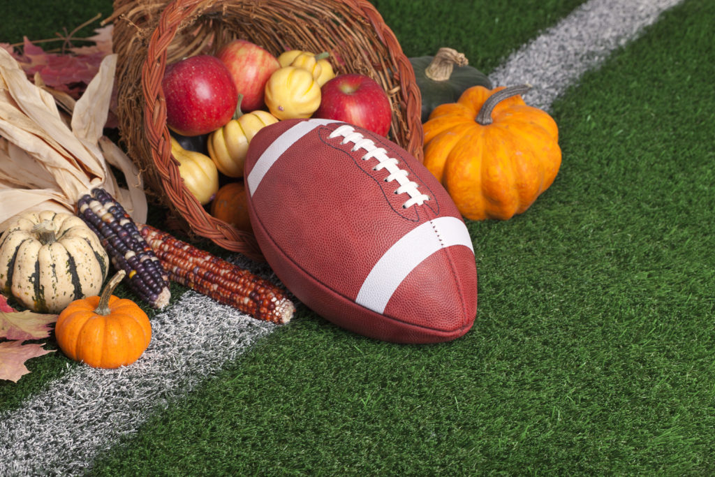 A college style football with a cornucopia on a grass field with white stripe